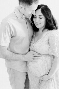 black and white maternity photo of mom and dad holding bump; what to pack for hospital or birth center
