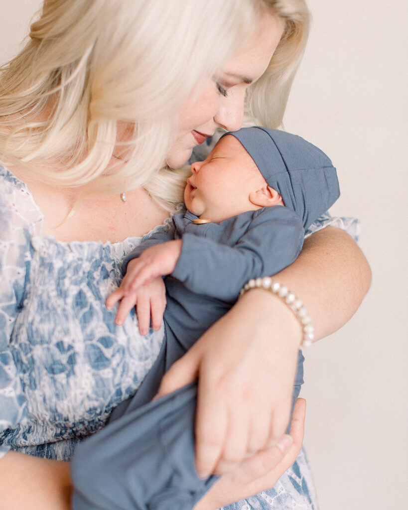 Close-up of a mother tenderly nuzzling her newborn’s forehead during a calm, styled studio session.
