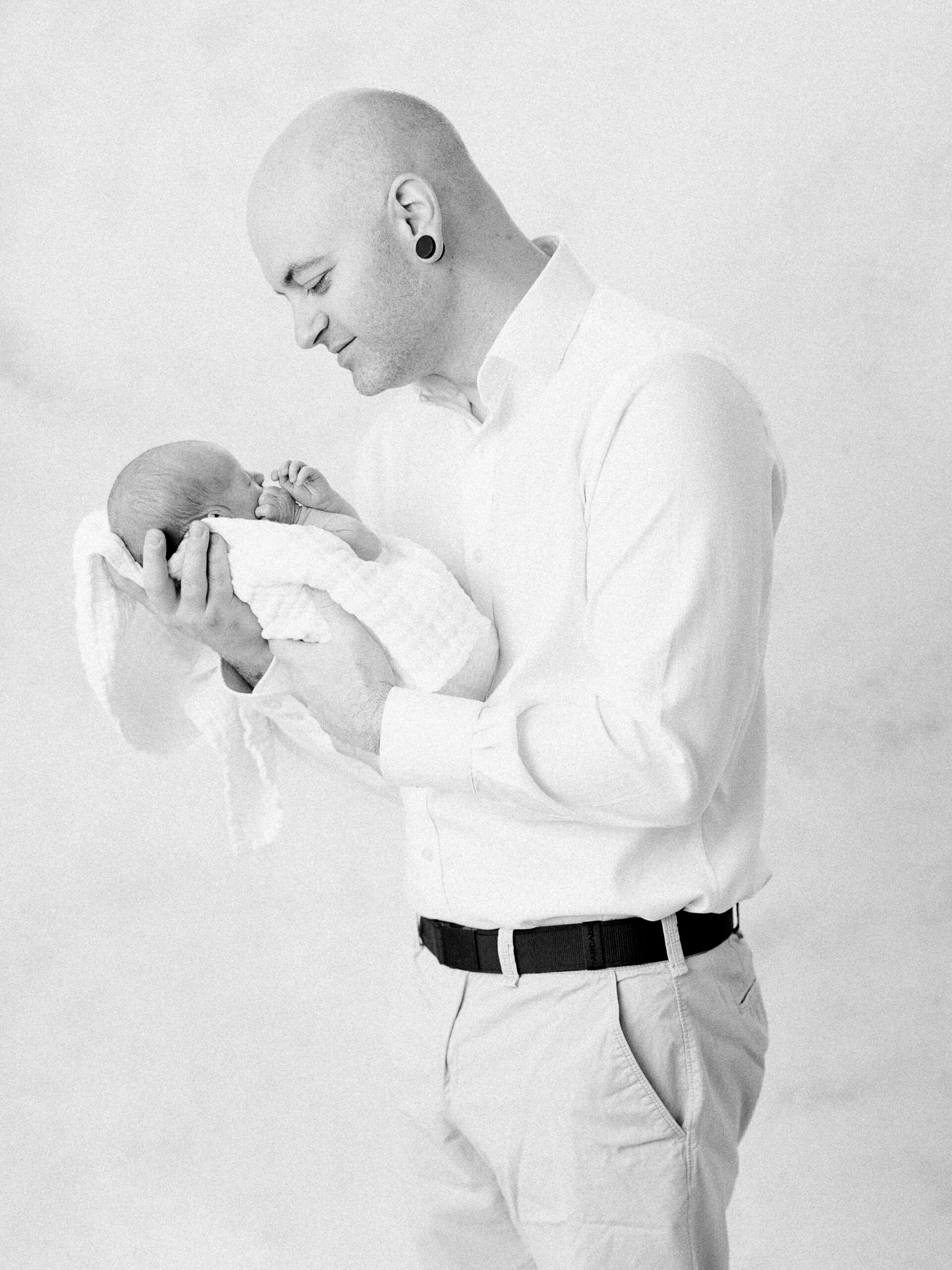 Dad holding and smiling down at newborn son