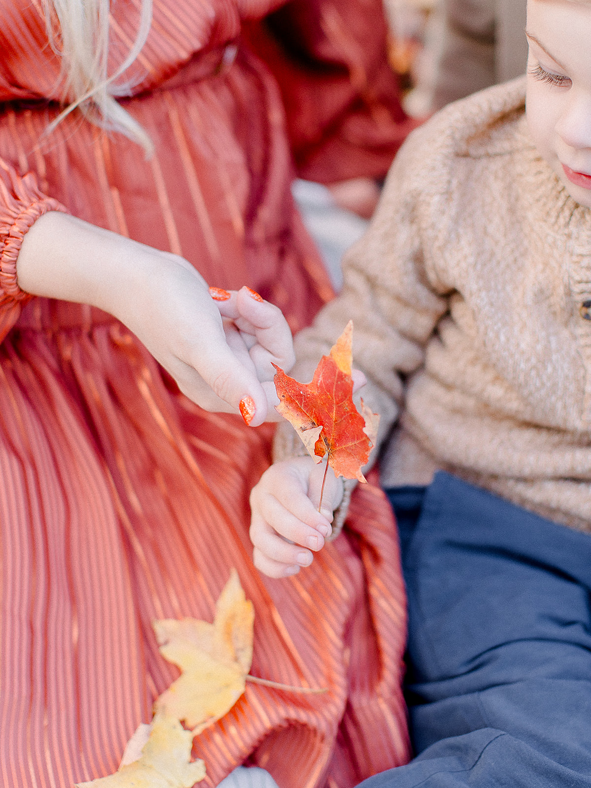 Child handing freshly fallen autumn leaves to his mother, gathered for a fall craft for kids in New England